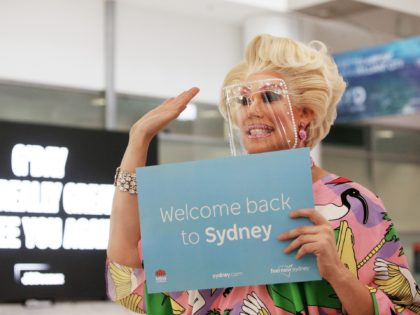 Drag queen Penny Tration waves to passengers on arrival at Sidney Airport on February 21, 2022 in Sydney, Australia. Australia is welcoming fully-vaccinated international travellers for the first time since closing its borders to all non-citizens and non-residents in March 2020 to limit the spread of COVID-19. (Photo by Lisa …