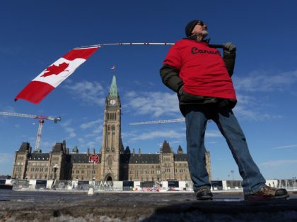 A man holds a Canadian flag near Parliament Hill as demonstrators continue to protest the vaccine mandates implemented by Prime Minister Justin Trudeau on February 7, 2022 in Ottawa, Canada. - Canadian authorities struggled Monday to tackle a truckers' protest against Covid restrictions which has paralyzed the national capital for …