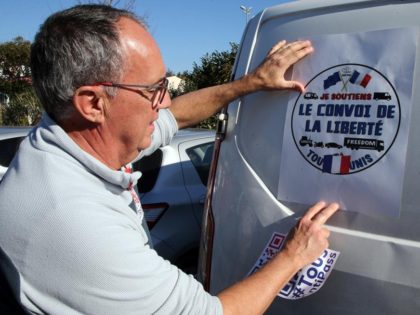 A man puts a poster reads "Liberty Convoy" on a van before leaving for Paris , in Bayonne, southwestern France, Wednesday, Feb.9, 2022. Paris police on Thursday Feb.10, 2022 banned road blockades threatened by groups organizing online against COVID-19 restrictions, in part inspired by protesters in Canada. (AP Photo/Bob Edme)