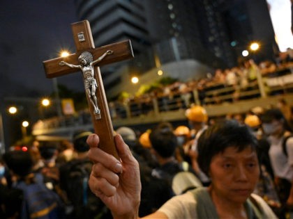 A protester holds a Christian cross as others gather outside the police headquarters in Hong Kong on June 21, 2019. - Thousands of protesters converged on Hong Kong's police headquarters on June 21, demanding the resignation of the city's pro-Beijing leader and the release of demonstrators arrested during the territory's …