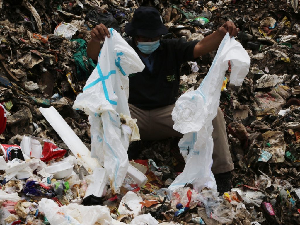 A worker shows discarded personal protective equipment (PPE) found at the Burangkeng landfill where most of the medical waste from Covid-19 hospital wards are collected, in Bekasi on October 19, 2021. (Photo by Dasril Roszandi / AFP) (Photo by DASRIL ROSZANDI/AFP via Getty Images)