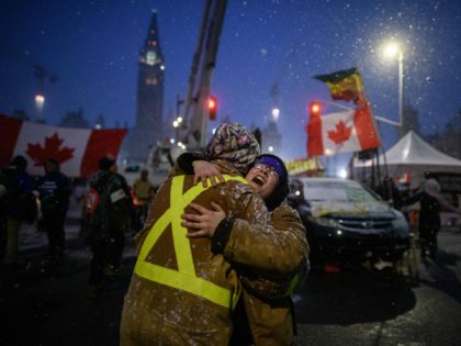 TOPSHOT - Demonstrators embrace during a protest by truck drivers over pandemic health rul