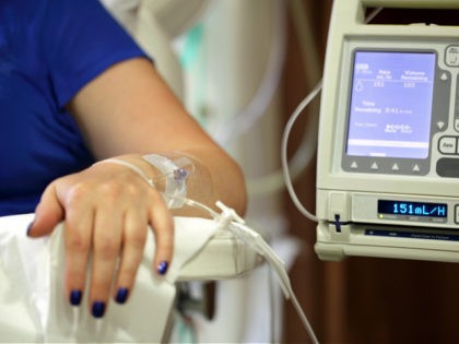Infusion pump feeding IV drip into patient arm focus on needle