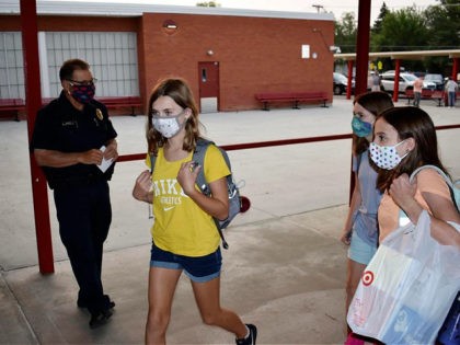 Students wearing masks enter Lewis and Clark Middle School for the first day of classes as school Resource Officer George Zorzakis, left, looks on in Billings, Mont. on Monday, August 24, 2020. Public school districts statewide are offering at least some level of in-person instruction, ranging from full-time to a …