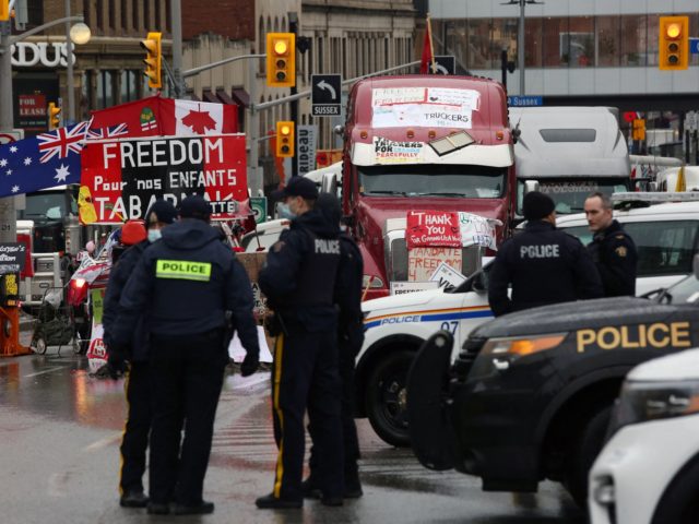 Police officers stand watch in downtown Ottawa, canada as demonstrators continue to protest the vaccine mandates on February 17, 2022. - Canadian police massed in the capital Thursday, readying to clear a trucker-led protest that has choked Ottawa's streets and provoked the government to call on rarely-used emergency powers. (Photo …