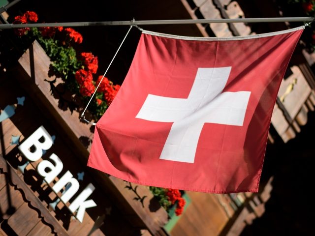 A sign "Bank" is seen beneath a Swiss flag on the front of a local banking branch on August 22, 2017 in Gstaad. (Photo by FABRICE COFFRINI/AFP via Getty Images)