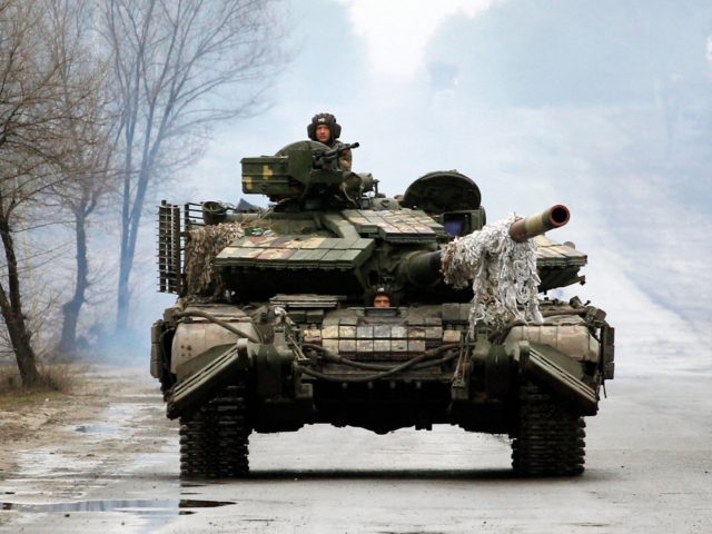 Ukrainian servicemen ride on tanks towards the front line with Russian forces in the Lugan