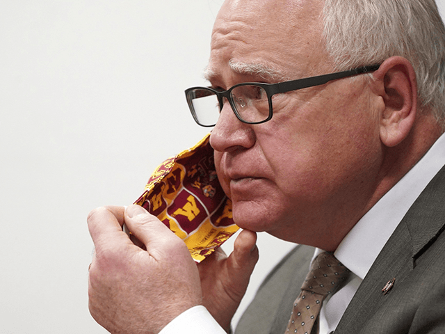 In this Jan. 26, 2021 file photo, Minnesota Gov. Tim Walz takes off his University of Minnesota cloth face mask to answer a question from a reporter during a press conference in St. Paul, Minn. Gov. Walz is quarantining for 10 days after being exposed to a staff member who …