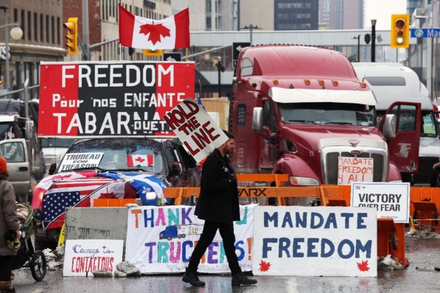 A protester walks in front of parked trucks as demonstrators continue to protest vaccine m