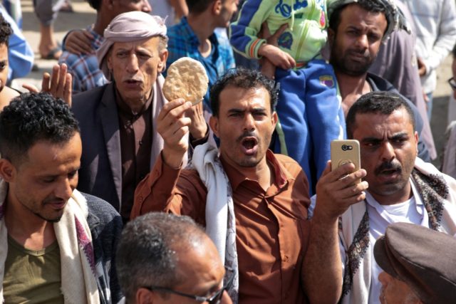 A Yemeni man holds up a piece of bread during a protest against the deteriorating economic