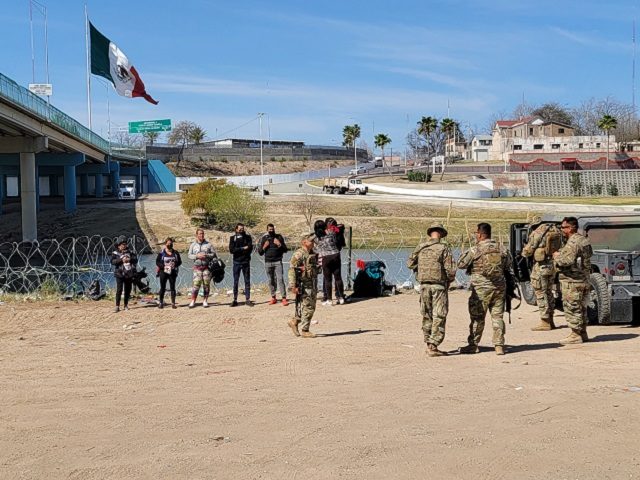 Texas National Guard soldiers hold a group of migrants while they wait for a Border Patrol