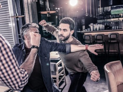 Angry bearded man going to beat his friend in a restaurant fight
