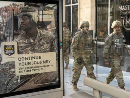 WASHINGTON, DC - January 19: National Guard troops walk past a recruitment sign for the Army National Guard on January 19, 2021 in Washington, DC. Tens of thousands of National Guard troops were deployed to DC following the January 6 insurrection at the Capitol. (Photo by Nathan Howard/Getty Images)