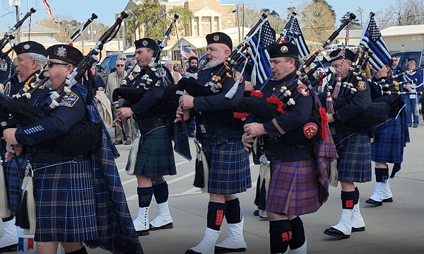 A multi-agency police bagpipe and drum corps march to honor Deputy Neil Adams. (Bob Price/Breitbart Texas)