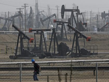In this Jan. 16, 2015, file photo, a person walks past pump jacks operating at the Kern River Oil Field in Bakersfield, Calif. California's oil rich Kern County is voting on a revised plan that could permit tens of thousands of oil and gas wells in the next two decades. …