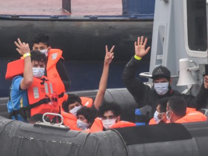 DOVER, ENGLAND - AUGUST 12: Migrants gesture as they arrive in port aboard a Border Force