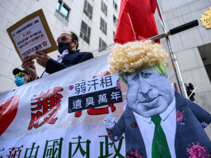 A caricature of British Prime Minister Boris Johnson (C) is displayed by pro-Beijing activists as they gather outside the British Consulate-General to protest against the use of the British National (Overseas) passport in Hong Kong on February 1, 2021, as a new visa scheme offering millions of Hong Kongers a …