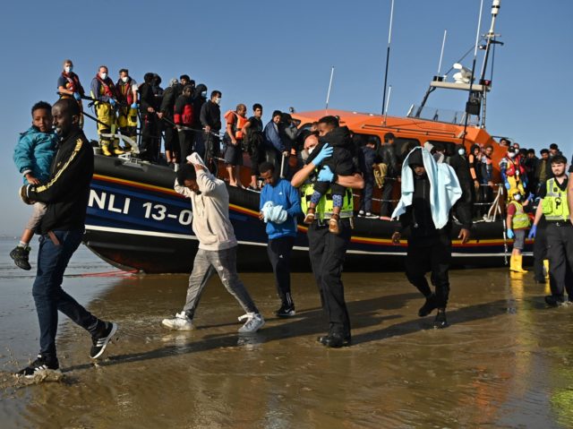 TOPSHOT - Migrants with children are escorted to be processed after being picked up by an RNLI (Royal National Lifeboat Institution) lifeboat while crossing the English channel at a beach in Dungeness, southeast England on September 7, 2021. (Photo by Ben STANSALL / AFP) (Photo by BEN STANSALL/AFP via Getty …