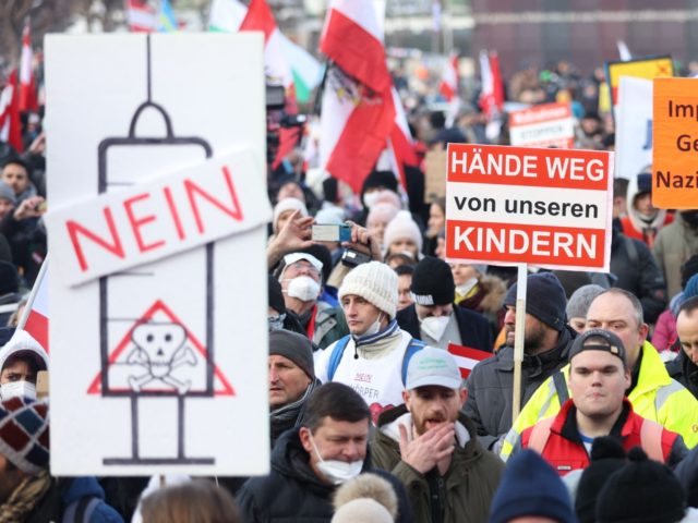 People demonstrate against the Austrian government's measures taken in order to limit the spread of the coronavirus during a protest on January 8, 2022 in Vienna, amid the novel coronavirus / COVID-19 pandemic; placard in (C) reads: "Hands off our children" and at (R) "Compulsory vaccination for recovered people is …