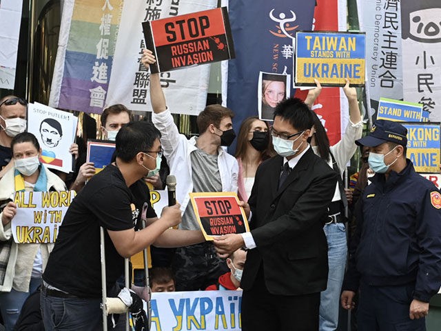 A staff member (centre R) from the Russian representative office receives a protest sign f