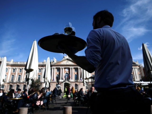 A waiter crosses the road to serve his customers on the terraces set up on the place du Capitole, in Toulouse, southern France, on February 25, 2022. - Terrace extensions permitted in Toulouse to compensate the lack of activity in restaurants and bistros due to Covid- 19 restrictions are causing …
