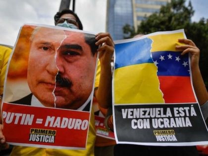 An activist member of opposition party Primero Justicia holds a placard showing the face of Russian President Vladimir Putin and Venezuelan President Nicolas Maduro during a protest against the Russian invasion in Ukraine, in Caracas on March 4, 2022. (Photo by Federico PARRA / AFP) (Photo by FEDERICO PARRA/AFP via …