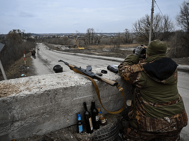 An Ukrainian serviceman looks through binoculars towards the town of Stoyanka at a checkpoint before the last bridge on the road that connects Stoyanka with Kyiv, on March 6, 2022. (Photo by ARIS MESSINIS / AFP) (Photo by ARIS MESSINIS/AFP via Getty Images)