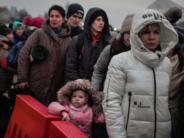 Refugees wait for their transportation after crossing the border into Poland at the border