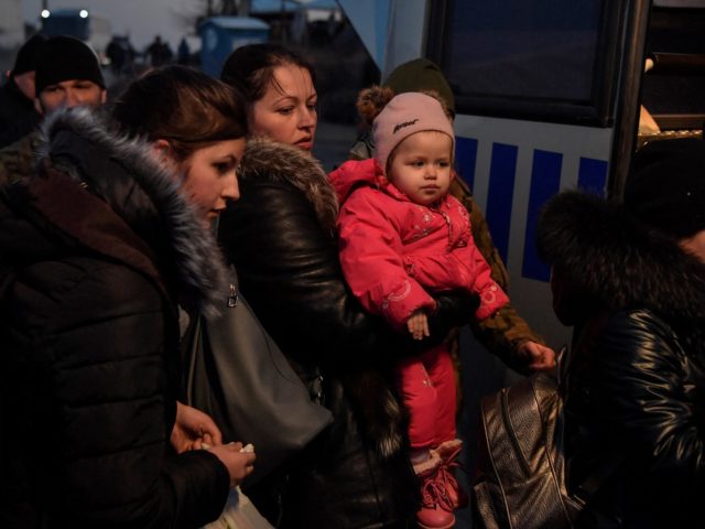 Refugees board a bus for further transport after crossing the Ukrainian border with Poland