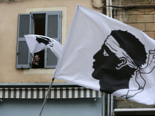 A woman waves from her window a Coriscan flag on March 13, 2022, during a rally in support