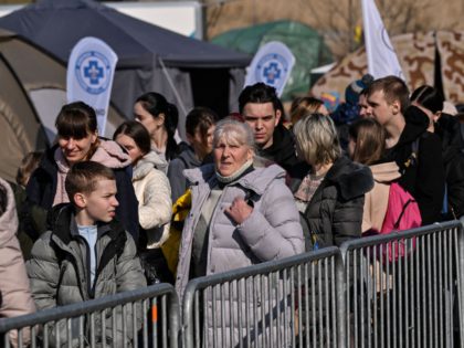 People stand as they wait to board buses for their further transportation after crossing from Ukraine into Poland at the Medyka border crossing on March 15, 2022. - More than three million people have now fled Ukraine since Russia invaded on February 24, the United Nations said on March 15, …