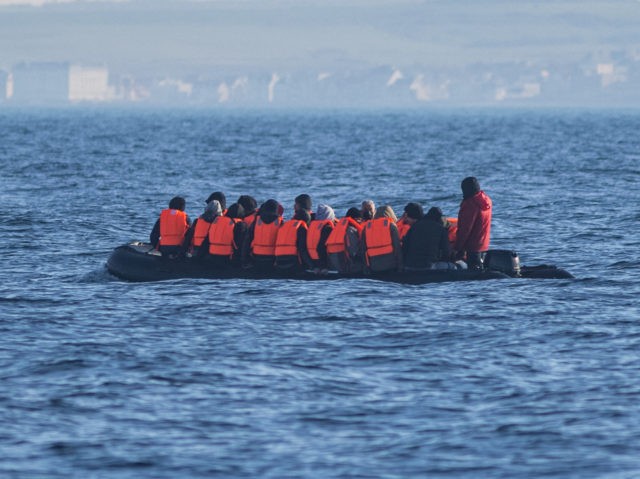 Migrants wearing life jackets sit in a dinghy as they illegally cross the English Channel