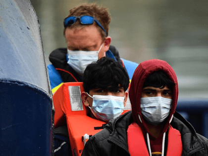 A UK coastguard helps migrants to disembark from the UK Border Force vessel Alert, after they were picked up at sea while attempting to cross the English Channel, and brought to the Marina in Dover, southeast England, on March 16, 2022. - The high number of migrants crossing to Britain …