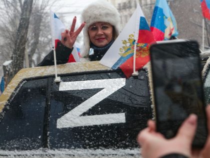 A woman poses for pictures from behind a car door with its window decorated with the letter "Z", which has become a symbol of support for Russian military action in Ukraine, during celebrations marking the eighth anniversary of Russia's annexation of Crimea in Simferopol on March 18, 2022. (Photo by …