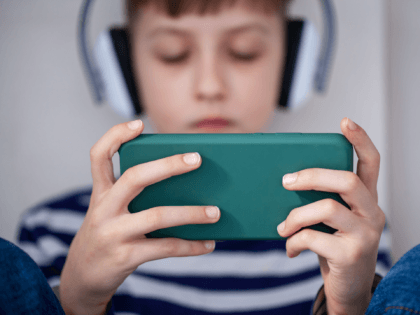 Child hands holding smartphone close-up for playing or learning. Concept kids using technology - stock photo