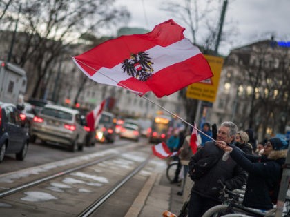 VIENNA, AUSTRIA - FEBRUARY 11: Anti-coronavirus lockdown measures and anti-vaccination protesters hold an Austrian flag in a gathering inspired by the current "Freedom Convoy" blockades in Canada on February 11, 2022 in Vienna, Austria. The Canadian "Freedom Convoy" protests have begun leading to similar protests elsewhere, including today in Austria …