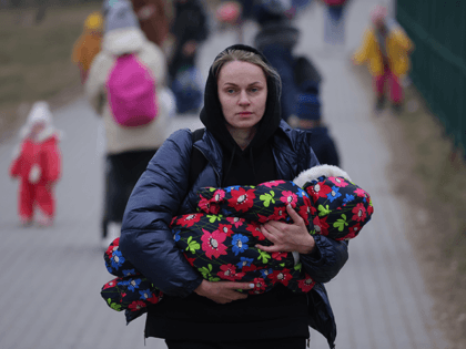 Women and children from war-torn Ukraine, including a mother carrying an infant, arrive in