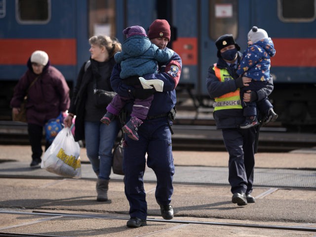 ZAHONY, HUNGARY - MARCH 07: A Hungarian policemen carry refugee children fleeing Ukraine a