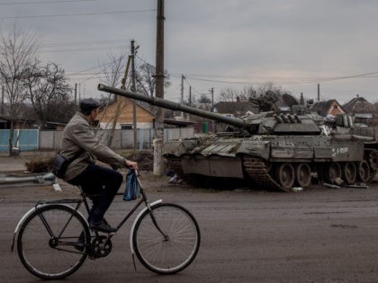 TROSTYANETS, UKRAINE - MARCH 30: A man rides his bike past a destroyed Russian tank on Mar