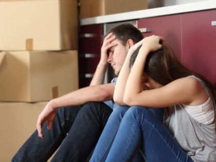 Angry evicted couple worried moving house sitting on the floor in the kitchen