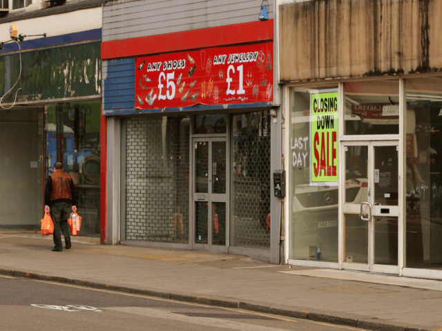 LONDON, ENGLAND - MARCH 13: A shopper walks past row of shops on Kilburn High Road on Marc