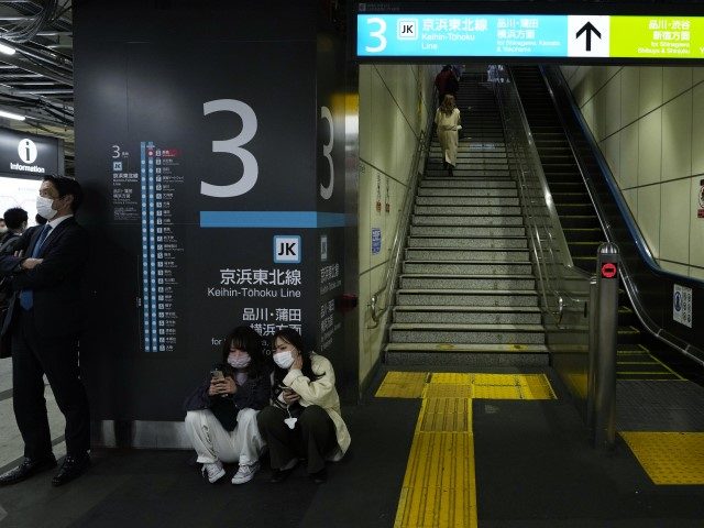 People wait for a train service to resume at a Tokyo train station in Tokyo, early Thursda