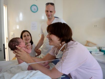 A midwife takes care of a newborn baby in front of their parents Helene Cordeau and Steven Le Gouallec after the delivery on August 2, 2013, at 'Les Lilas' maternity hospital in Les Lilas, a northeastern Paris suburb.