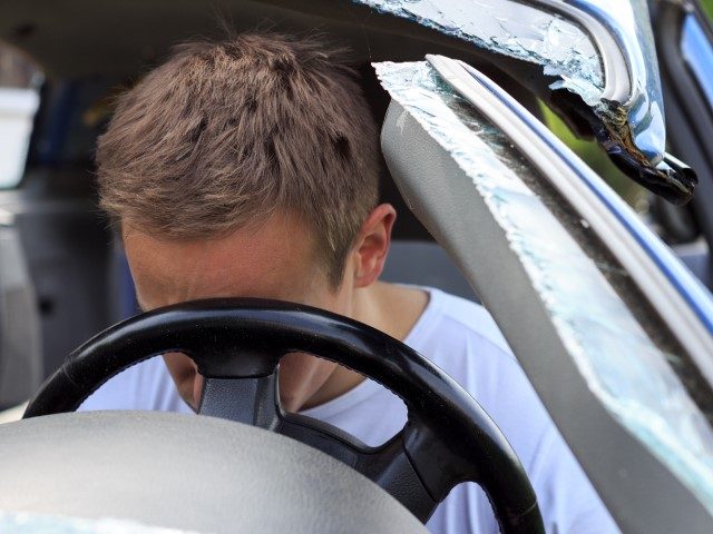 Man lies injured in car after an accident.