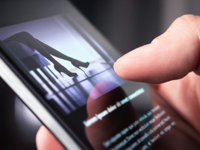 Man looking at a photo of a woman in high heels with smartphone.