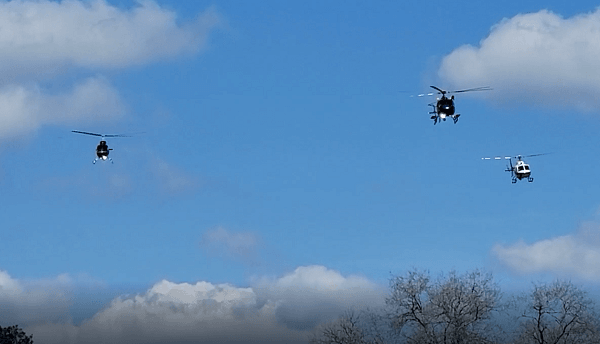 Police helicopters fly over the memorial service for Deputy Neil Adams in the Missing Man formation. (Bob Price/Breitbart Texas)