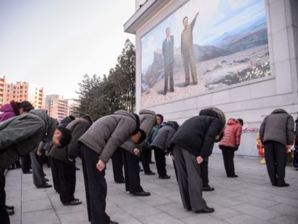 People bow to pay their respects in front of a mosaic that shows a depiction of President Kim Il Sung and Kim Jong Il, to mark the ten-year anniversary of the death of Kim Jong Il, the father of current leader Kim Jong Un, in Pyongyang on December 17, 2021.