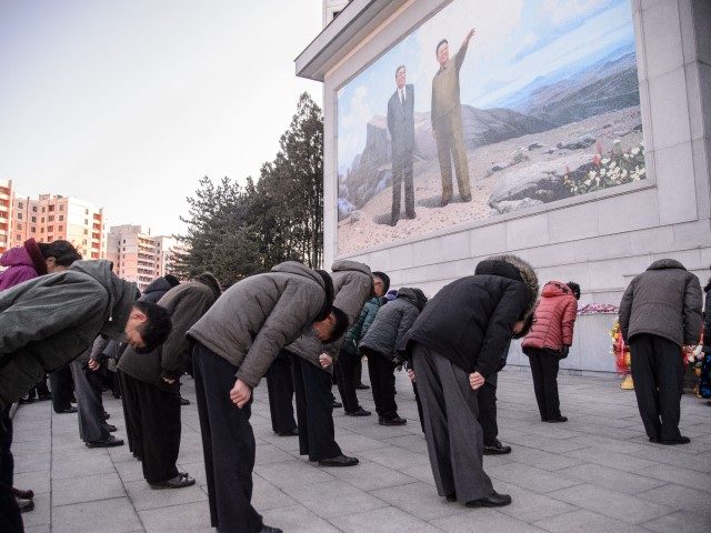 People bow to pay their respects in front of a mosaic that shows a depiction of President