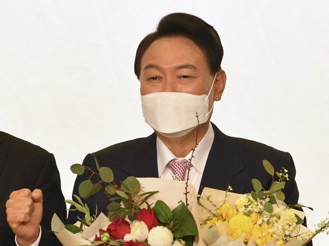 South Korea's president-elect Yoon Suk-yeol gestures while holding a bouquet during a cere