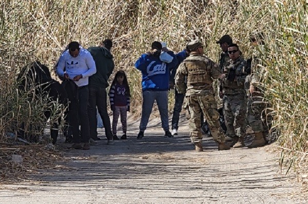 Texas National Guard Soldiers and Border Patrol agents process a group of migrants from three nations. The group included at least two family units. (A migrant woman celebrates the successful crossing of her family from Mexico into Texan. (Bob Price/Breitbart Texas))